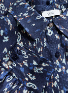 Close-up of navy printed blouse showing button cuff detail and fabric pattern texture.