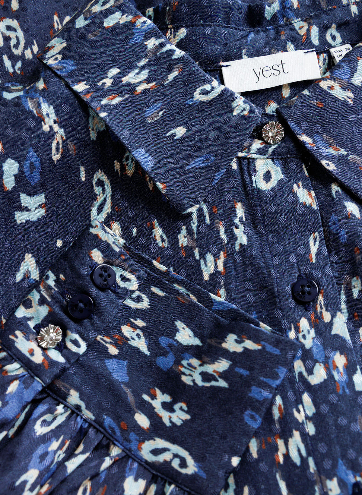 Close-up of navy printed blouse showing button cuff detail and fabric pattern texture.