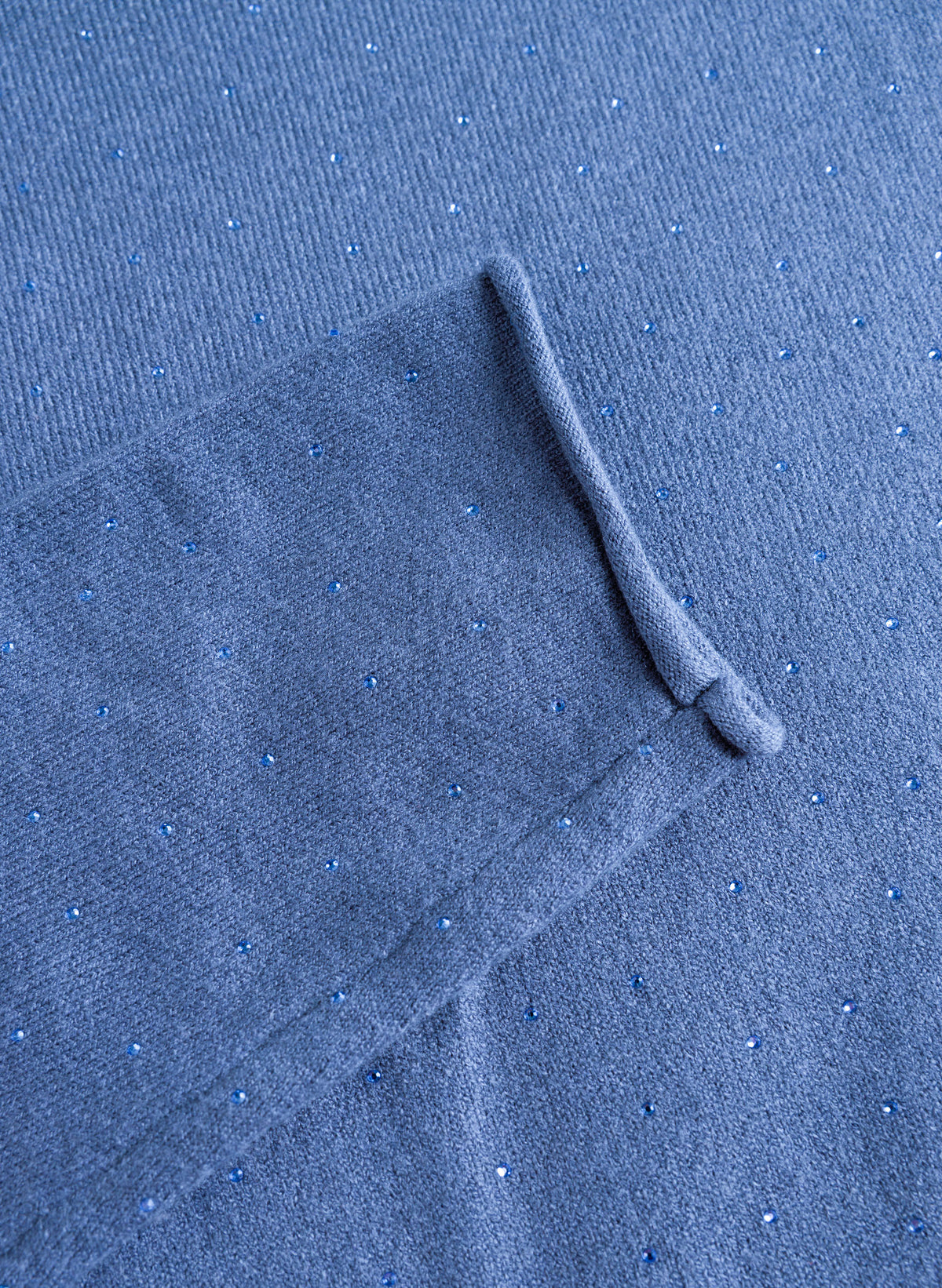 Close-up of blue turtleneck sweater's sparkle detailing and ribbed cuff texture.