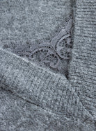Close-up of grey sweater's scalloped lace trim detail against a soft, brushed knit texture.