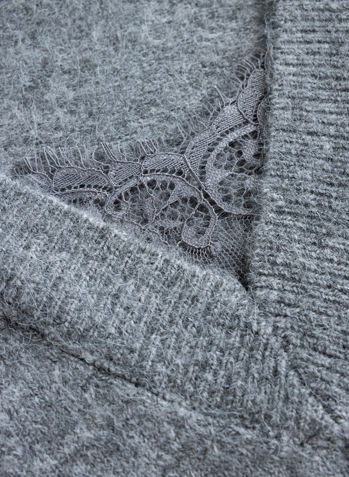 Close-up of grey sweater's scalloped lace trim detail against a soft, brushed knit texture.