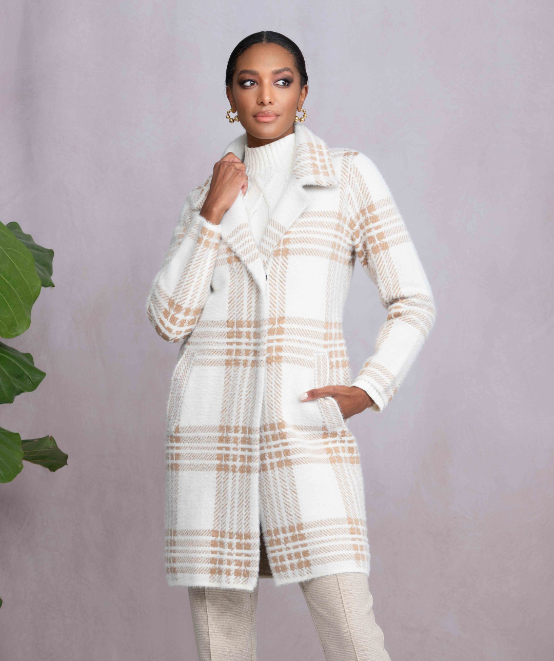 Woman wearing a white plaid coat and beige pants against a light purple background