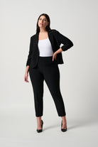 Plus sized woman wearing a black suit with a white top on a light gray background