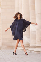 Woman in a navy blue dress standing in front of classical columns