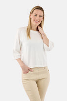 Woman wearing a white top and beige pants on a white background