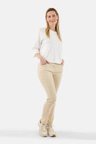 Woman wearing a white sweater and beige pants on a white background