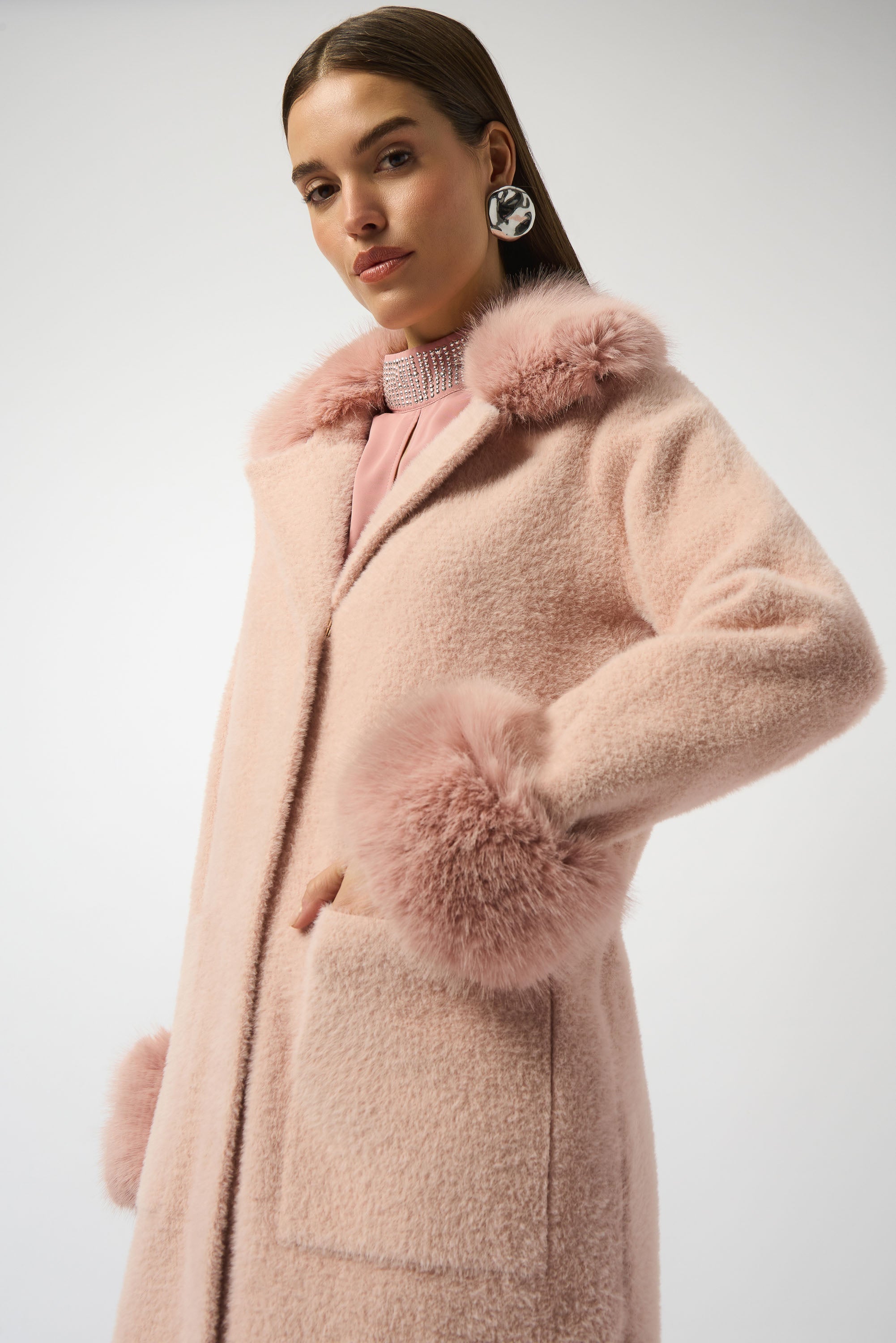 Close Up of woman wearing a pink coat with fur accents on a white background