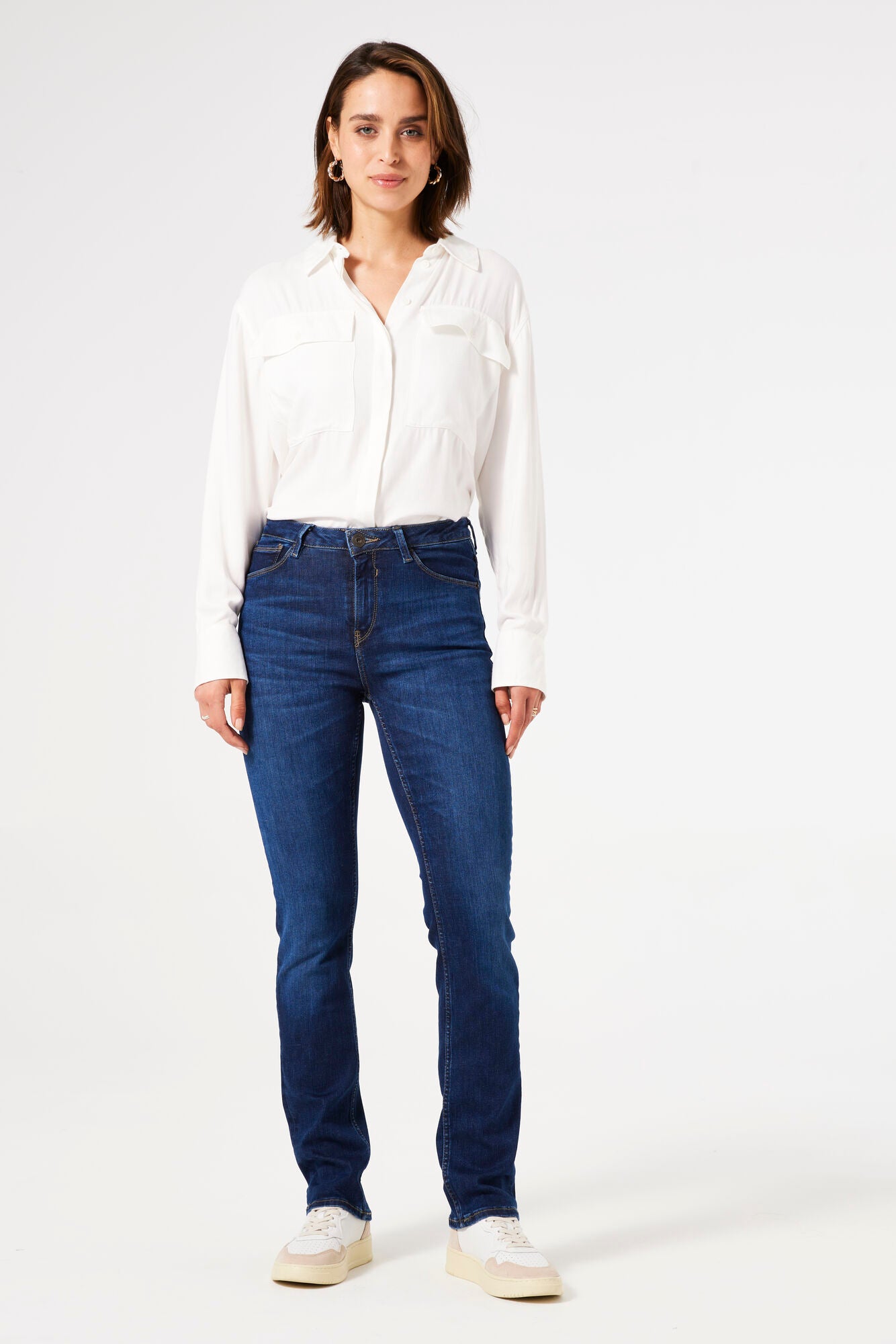 Woman wearing mid-rise straight-leg denim jeans with a fitted hip and clean five-pocket styling, front view.