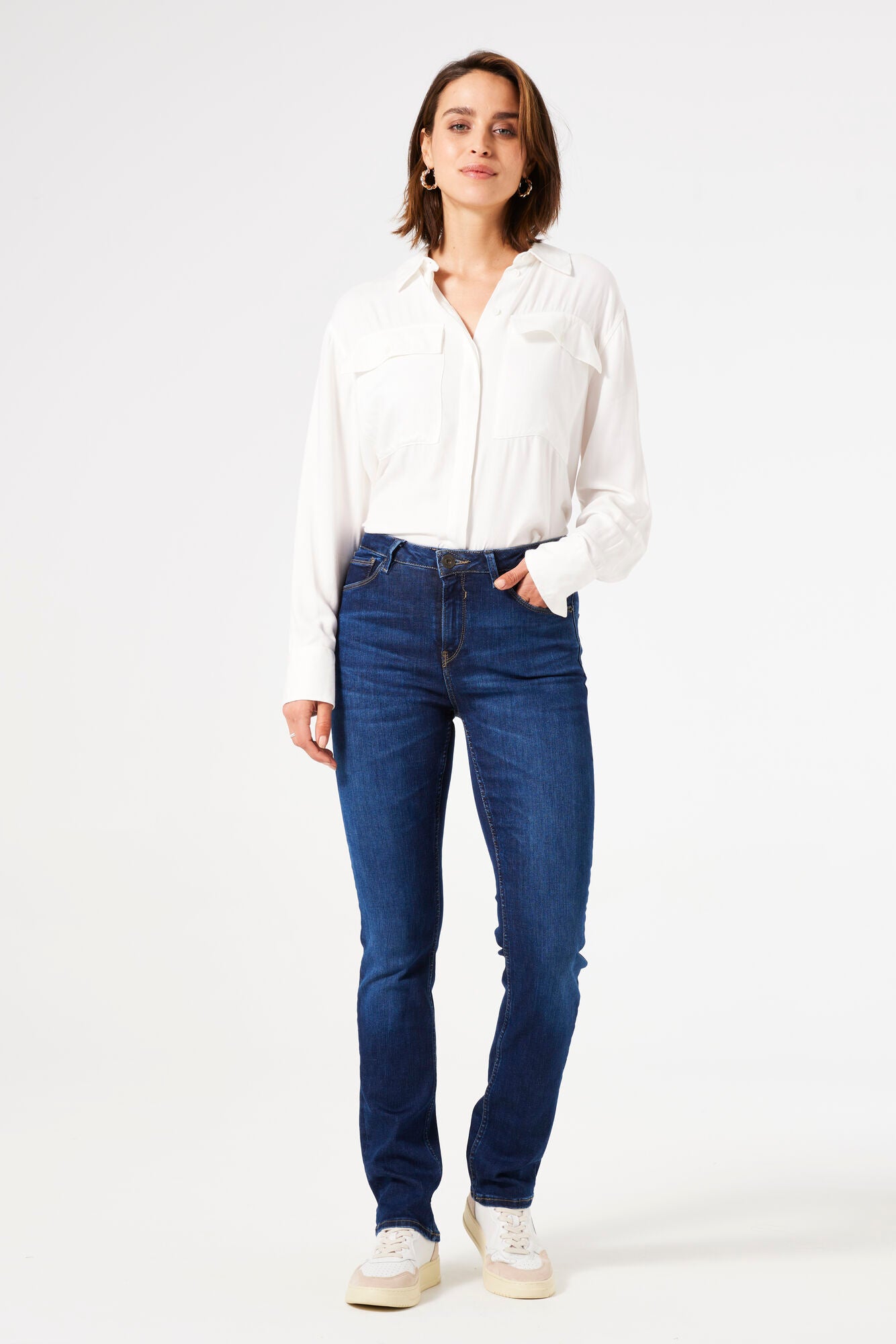 Woman wearing mid-rise straight-leg denim jeans with a fitted hip and clean five-pocket styling, front view.