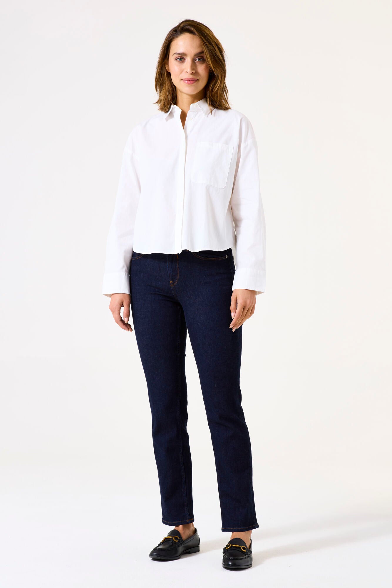 Woman wearing mid-rise straight-leg denim jeans with a fitted hip and clean five-pocket styling, front view.