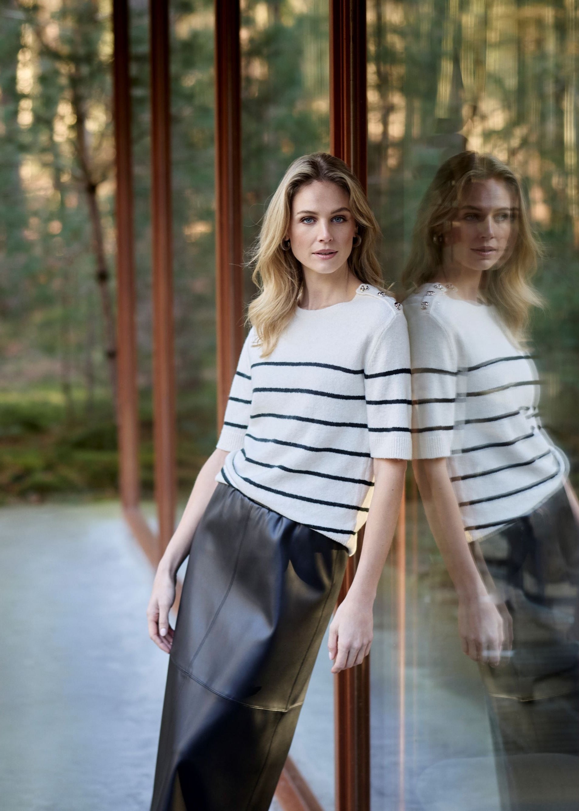 Woman standing in front of a glass door with a forest background