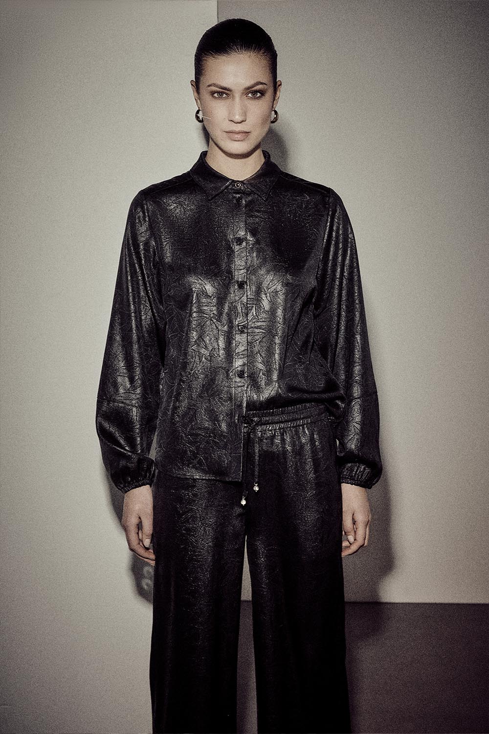 Person wearing a black textured outfit against a plain background