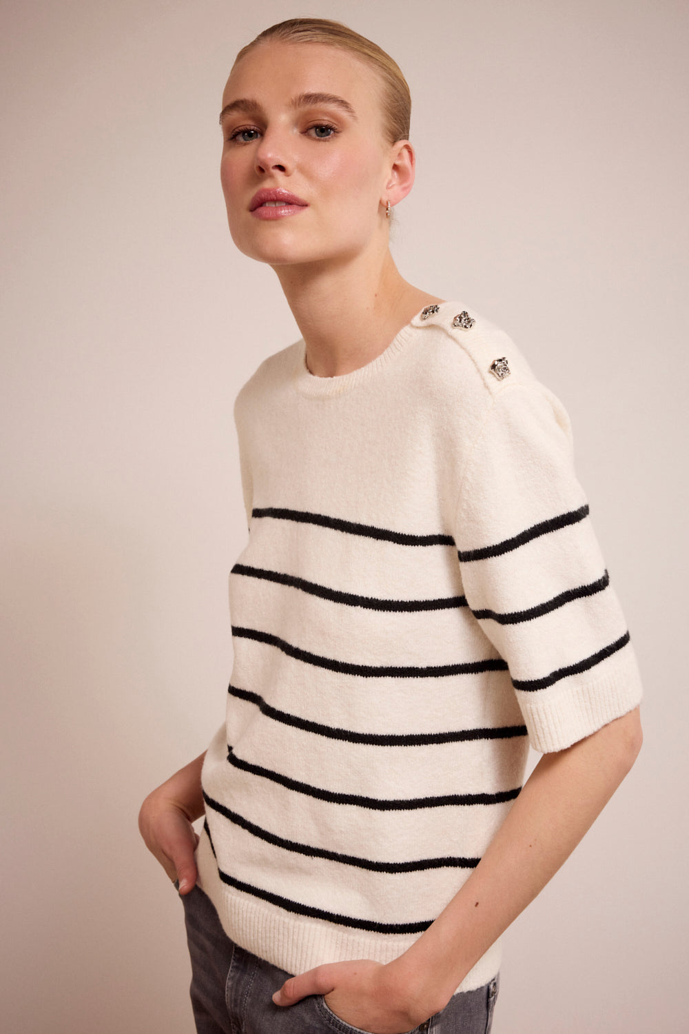 Person wearing a white sweater with black stripes on a plain background