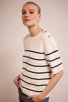 Person wearing a white sweater with black stripes on a plain background