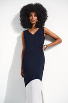 Model in a sleeveless navy and white midi dress with side slit details.