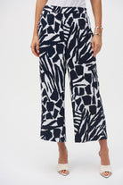 Woman wearing wide-leg, abstract print pants in navy and white, shown from the front with flat waistband and relaxed silhouette.