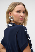 Close-up side view of a woman wearing the abstract print blouse, highlighting a large silver statement earring.