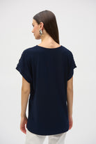 Woman wearing a navy short-sleeve top, back view showing smooth fabric and relaxed fit.