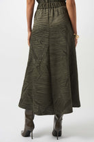 the back of a woman standing, wearing a long dark green skirt
