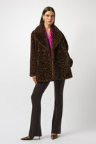Woman wearing a leopard print coat and black pants on a white background