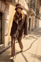 Woman in leopard print coat and fur hat walking on a city street.