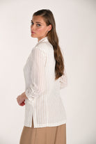 Model wearing a white pinstripe relaxed-fit blazer with ruched sleeves and lapel collar, styled with a sleeveless top and wide-leg trousers.