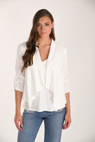 Front view of a women’s white lightweight drape jacket with ruched sleeves and an open cascading front paired with light wash jeans.