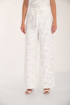 Close-up front view of floral lace wide-leg pants with a self-tie waistband and wide-leg design.
