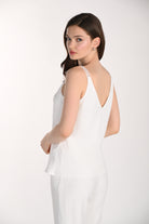 Woman wearing a white V-neck camisole featuring delicate textured straps and a flattering V-back design. The relaxed-fit top is shown from the back and side, highlighting its fluid drape and lightweight fabric against a neutral studio background.