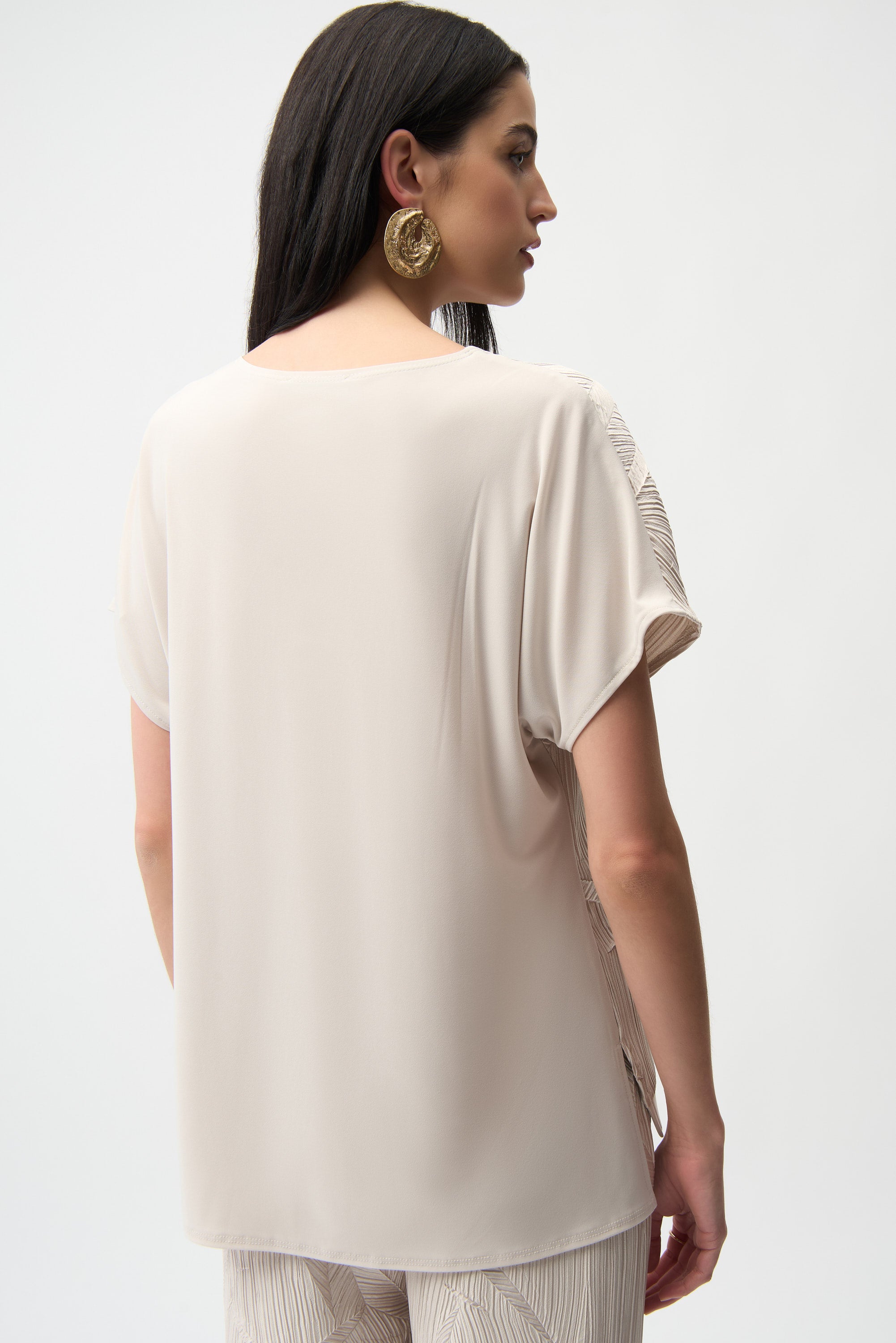 Back view of a woman wearing a Pleated Satin V-Neck Top, showcasing its elegant, relaxed styling and textured fabric.