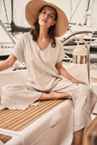 Woman wearing a Pleated Satin V-Neck Top sitting on a boat, showcasing relaxed style and elegance.