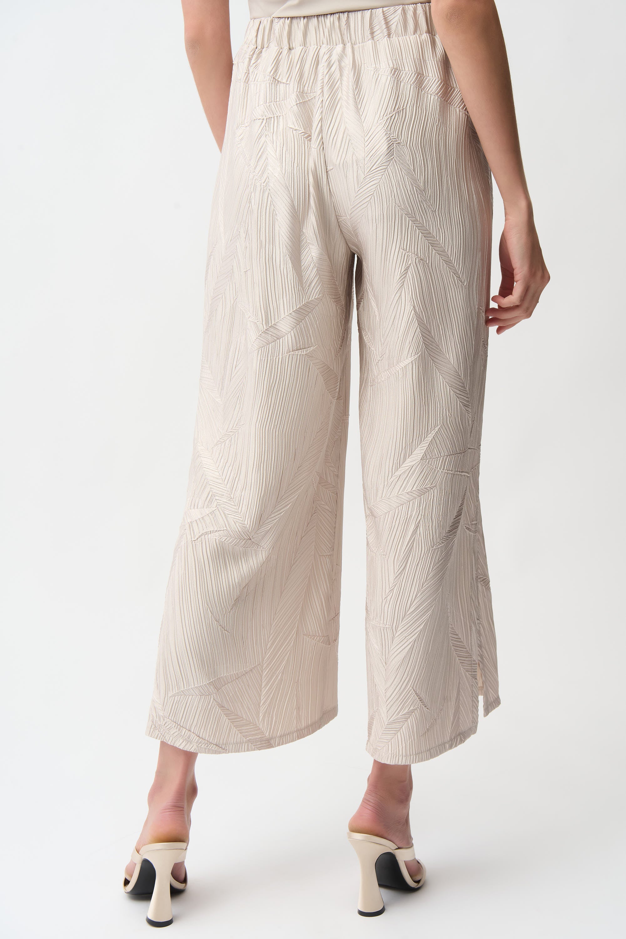 Back view of pleated satin pull-on culotte pants showcasing elegant pleats and side slits for modern style.