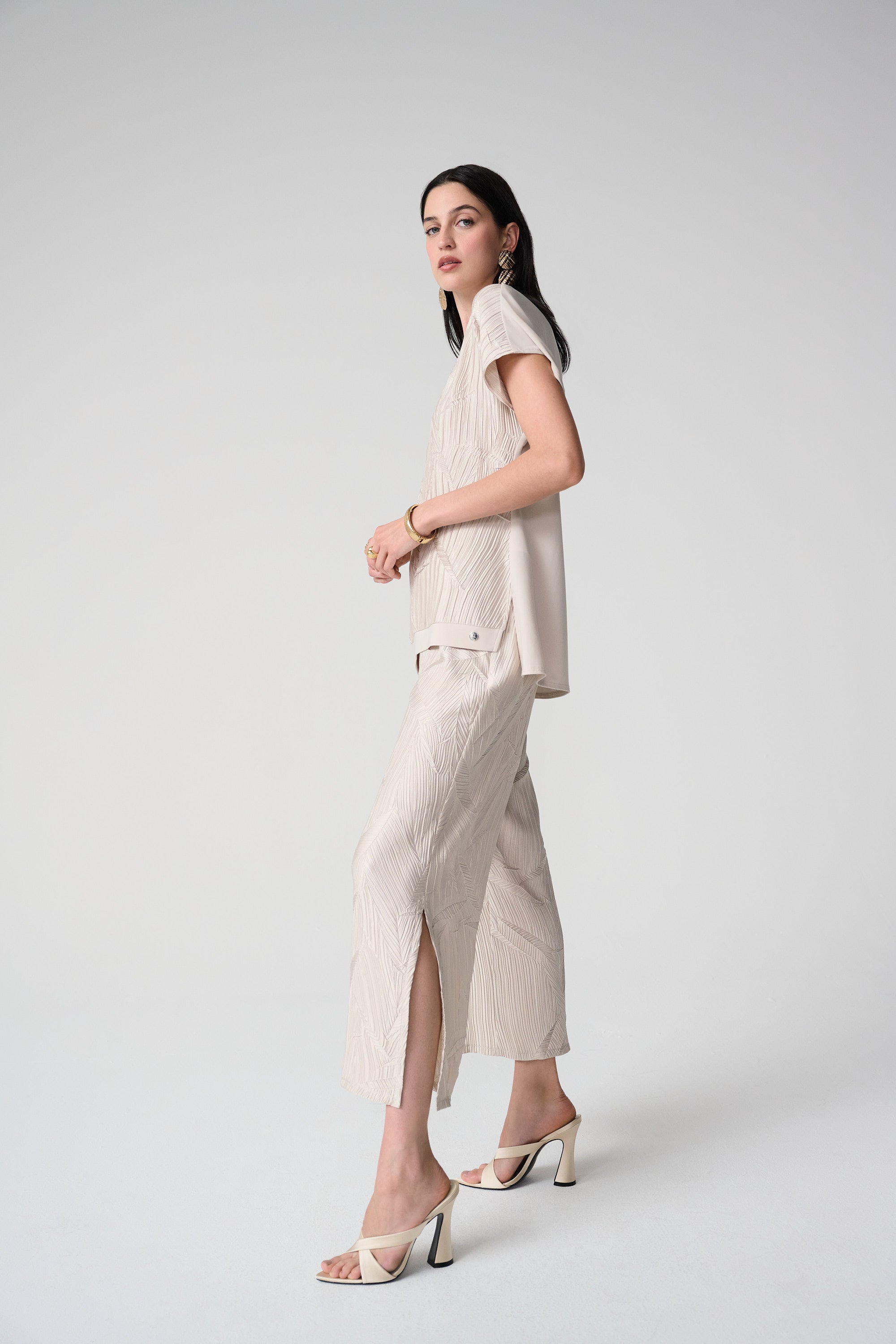Model wearing pleated satin pull-on culotte pants with a stylish top, showcasing elegant side slits and luxurious fabric.
