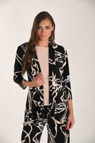 Woman wearing a lightweight abstract print throw-over with three-quarter sleeves and an open-front silhouette, layered over a sleeveless top and coordinating wide-leg pants.