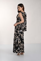 Side and back view of a women’s black sleeveless maxi dress with an abstract beige floral print, showcasing the layered overlay detail, relaxed drape, and back keyhole closure.
