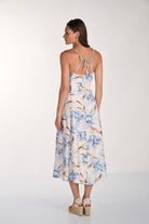 Women's blue floral midi slip dress with adjustable spaghetti straps, tie-back detail, and a flowing A-line silhouette. Back view showing the open-back design and midi-length hem.