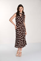 Women's sleeveless midi dress featuring an all-over polka dot print, tie-neck detail, fitted waist, and softly flared skirt. Shown from the front with ankle-strap heels. 