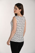 Model wearing a black and white polka dot sleeveless swing top with a relaxed fit and soft drape, shown from the back with black fitted pants.