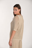 Side and back view of a beige metallic open-knit top featuring a relaxed silhouette, elbow-length sleeves, and a breathable mesh-knit texture. The lightweight sweater is styled with flowing wide-leg trousers, showcasing the drape and fit from the back.