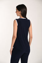 Back view of a women’s sleeveless navy knit top with white trim, featuring a relaxed fit and smooth drape paired with matching navy pants.