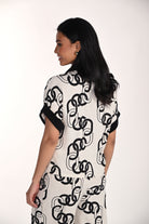 Back view of a woman wearing a relaxed chain print blouse with cuffed short sleeves and a soft, breathable drape. The all-over chain-inspired pattern and easy silhouette create a polished yet comfortable look.