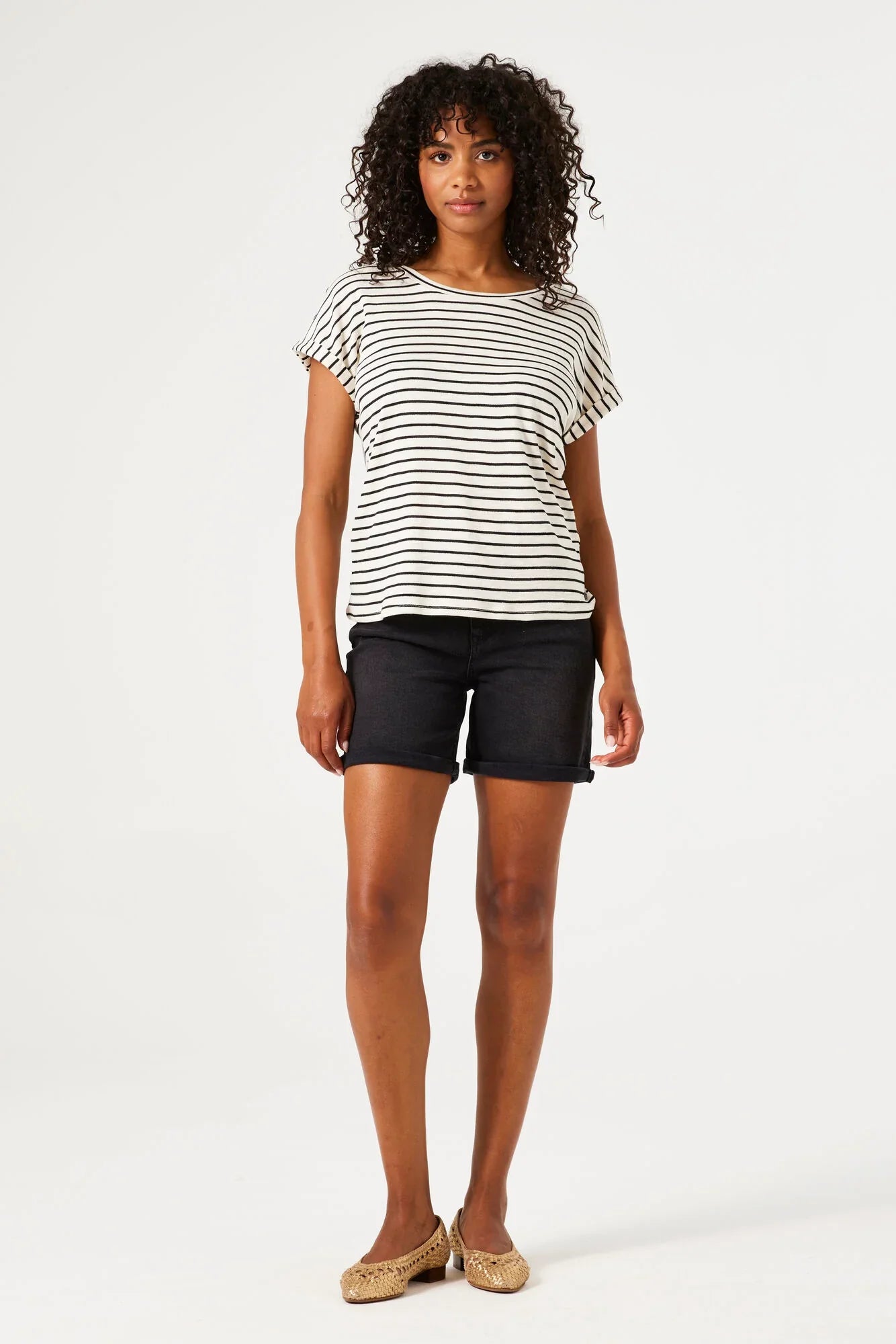 Woman wearing mid-length denim Bermuda shorts with rolled hem