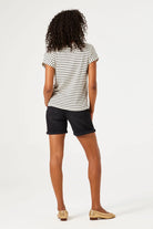 Woman wearing mid-length denim Bermuda shorts with rolled hems, shown from the back with a relaxed fit.