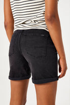 Close-up of the back of denim Bermuda shorts showing the fit, rolled hem, and rear pockets.