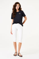 Front view of a woman wearing slim-fit capri pants paired with a short-sleeve top and flat sandals, showcasing the cropped silhouette.