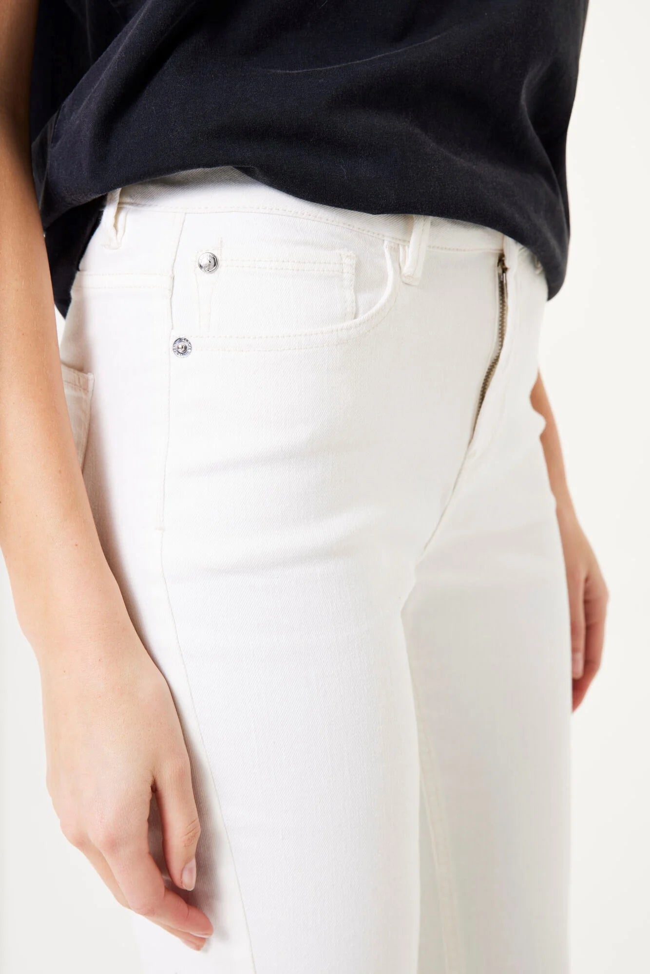 Close-up view of women’s capri pants showing the waistband, front pocket, and side zipper detail in a stretch fabric.
