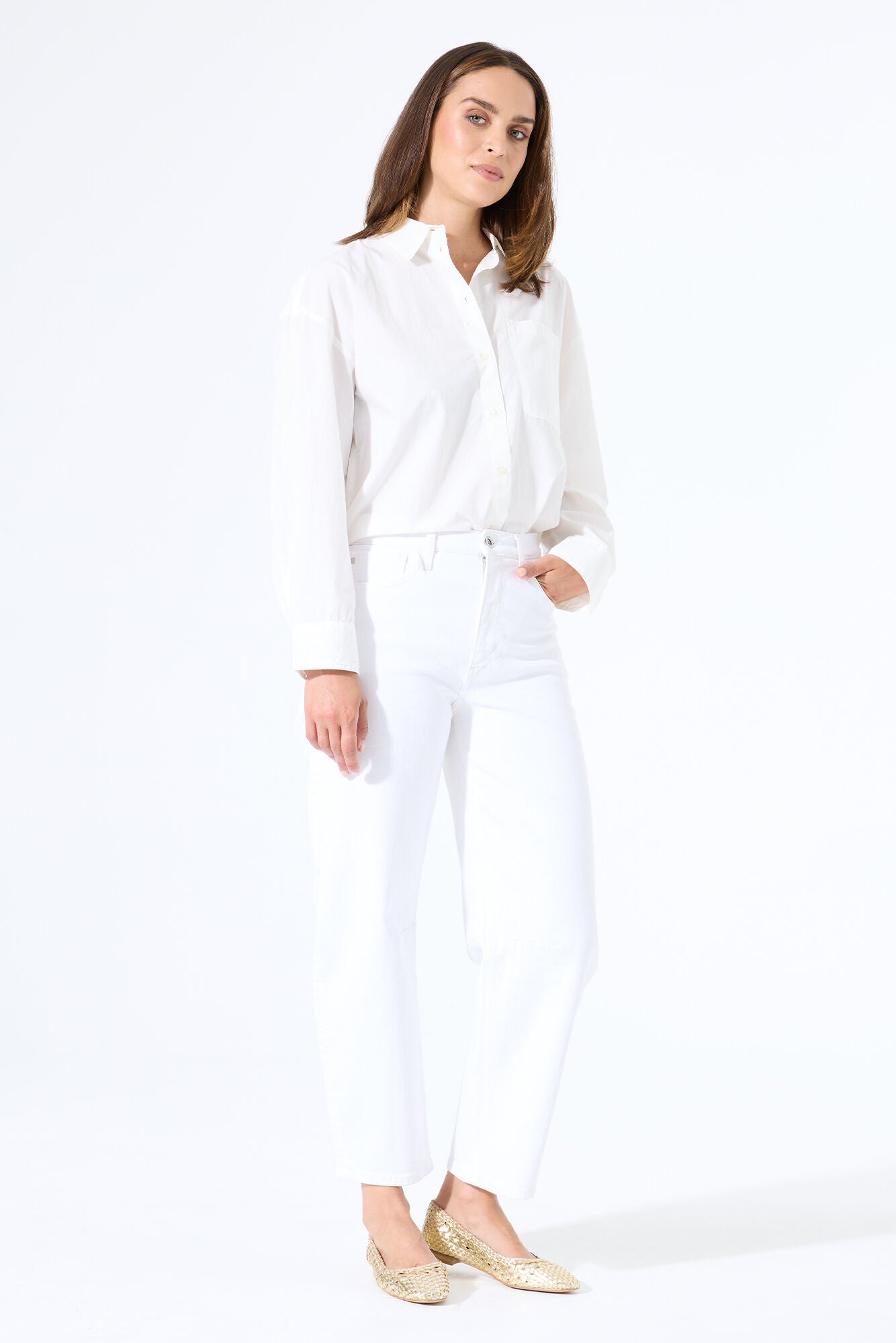 Model wearing white barrel-leg denim jeans with a button-up shirt tucked in, styled with flats for a clean, polished outfit.
