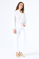 Model wearing white barrel-leg denim jeans with a button-up shirt tucked in, styled with flats for a clean, polished outfit.