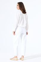 Model wearing white barrel-leg denim jeans with a button-up shirt tucked in, styled with flats for a clean, polished outfit.