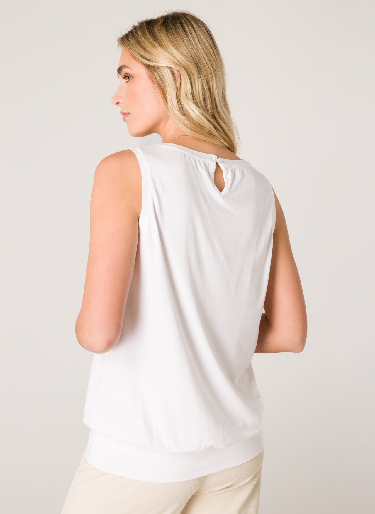 Back view of a women's white sleeveless blouse featuring a relaxed silhouette and subtle keyhole detail at the neckline.